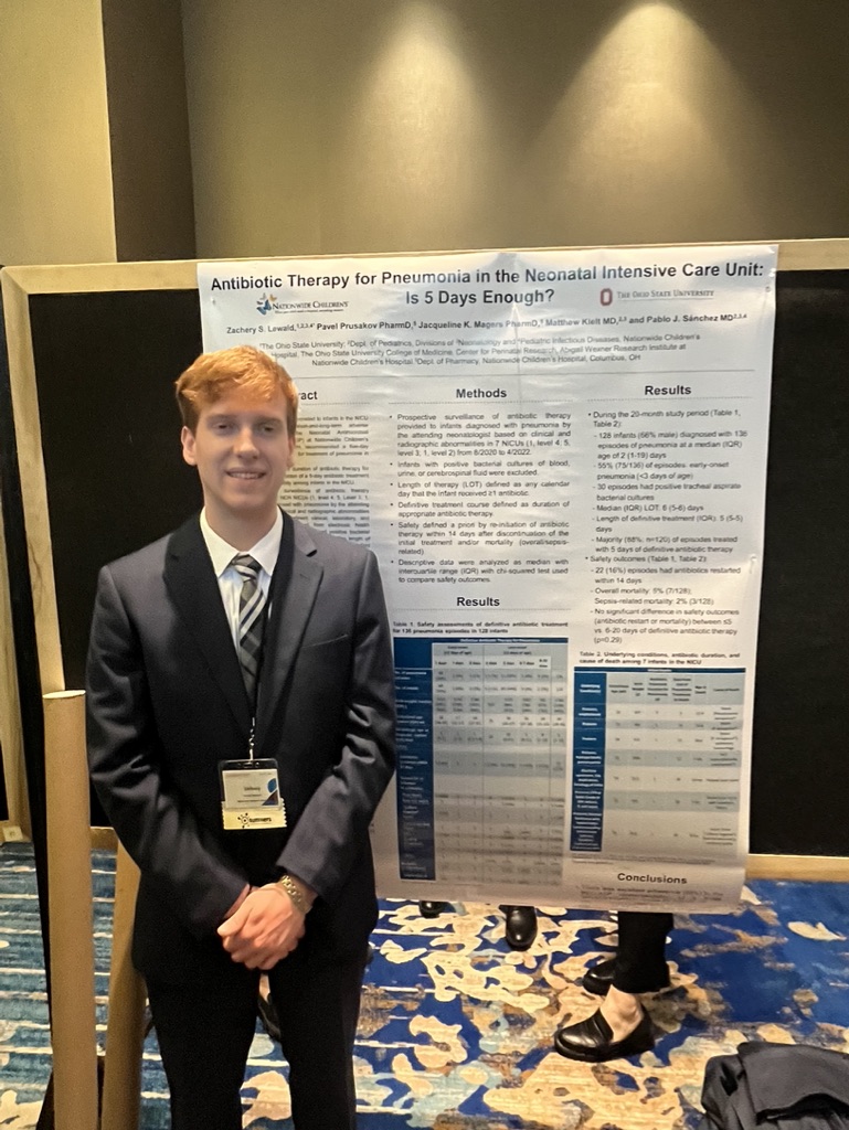 Zach Lewald standing beside his neonatal pneumonia research poster